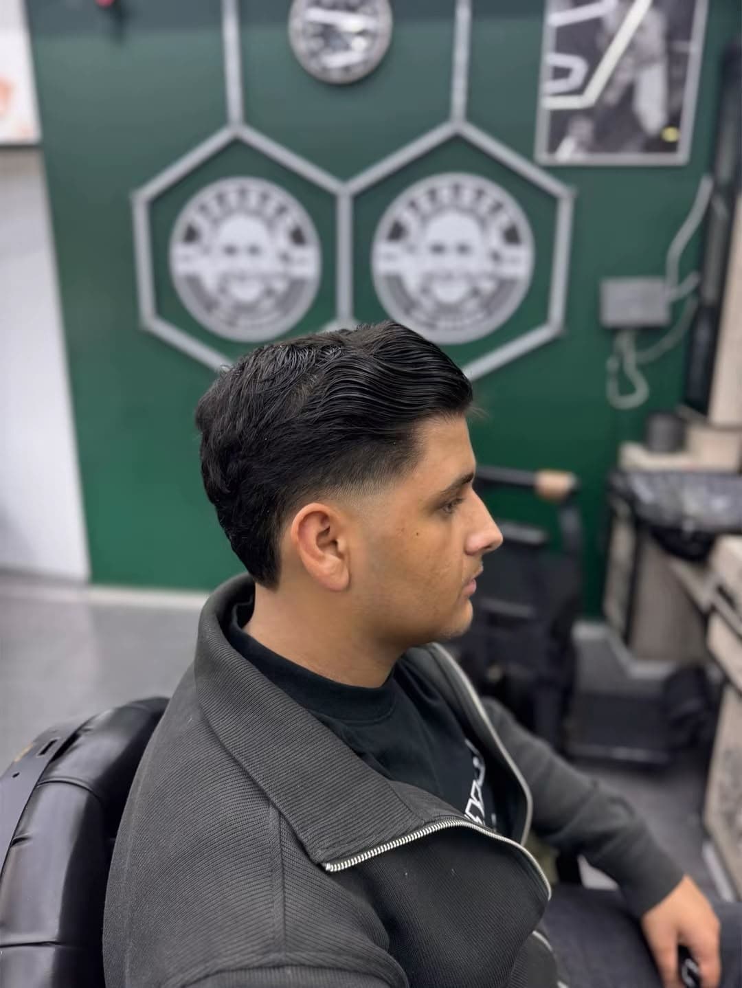 Side Part mit Low Fade vor der grünen Wand mit Berber-by-Memo-Logos